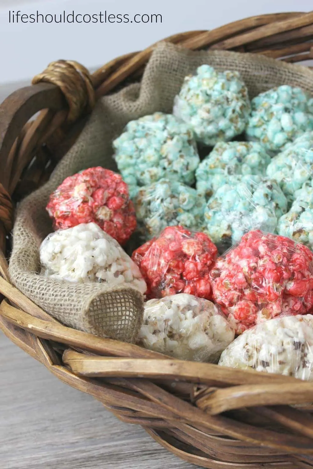 Red white and blue patriotic flag popcorn balls in large basket with burlap liner. {lifeshouldcostless.com}