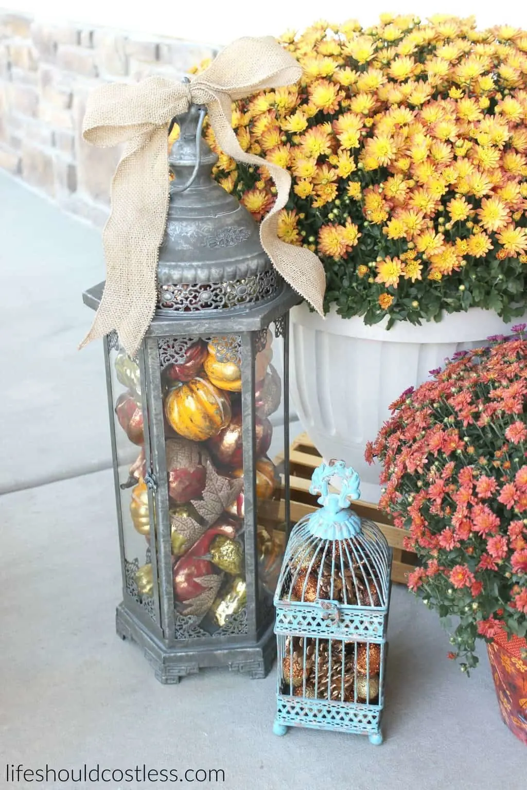 Rustic fall porch decor reveal. See this post and many more popular decor pins at lifeshouldcostless.com. Lantern and bird cage filled with fall decor.