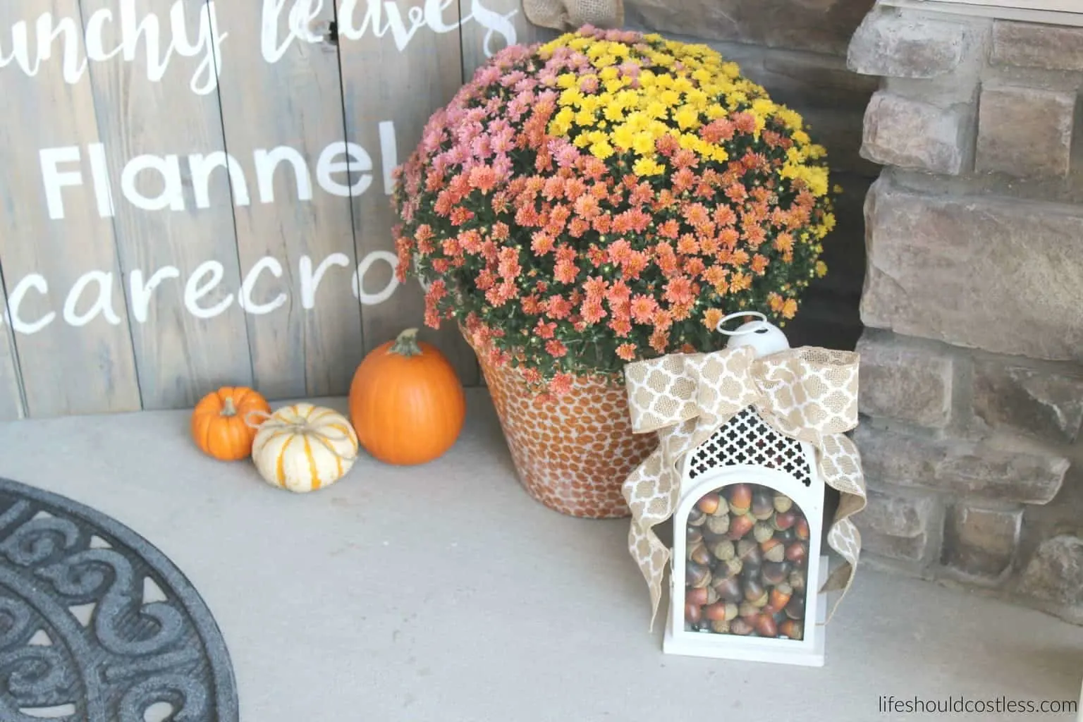 Rustic fall porch decor reveal. See this post and many more popular decor pins at lifeshouldcostless.com. Lantern filled with acorns.